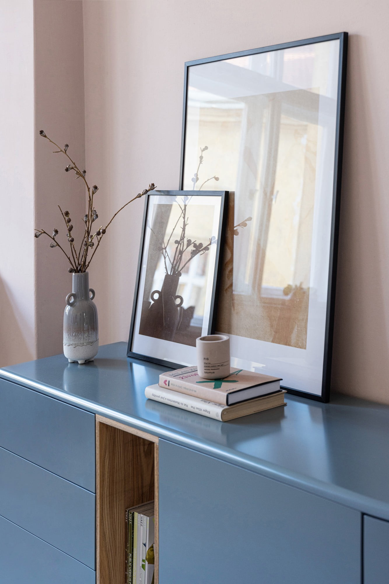 O vază rustică, o lumânare din beton și tablouri pentru un aspect dezinvolt.